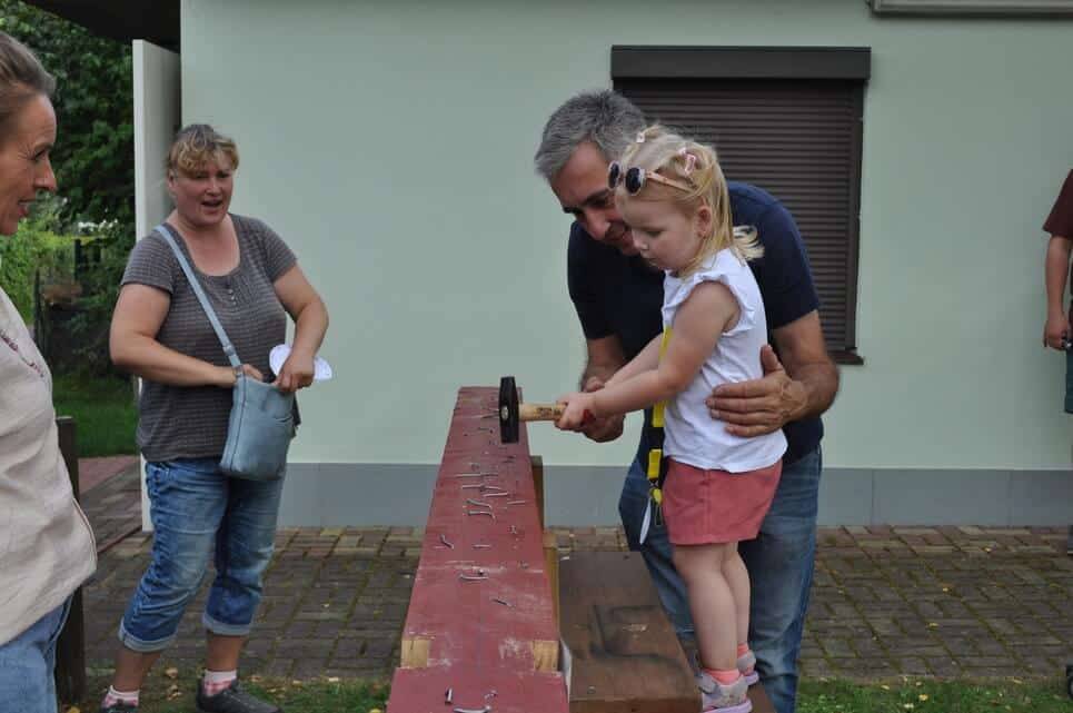 Ein Kleinkind wird beim Spielen auf einer roten Holzbahn gehalten.