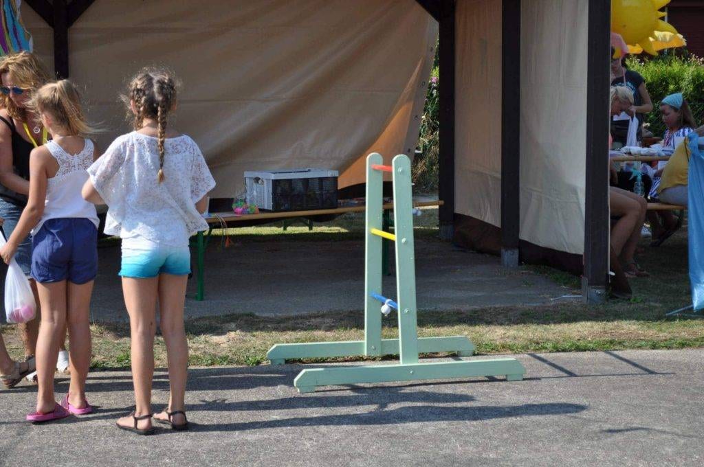 Drei Kinder warten vor einem Wurfspiel auf dem Festplatz.