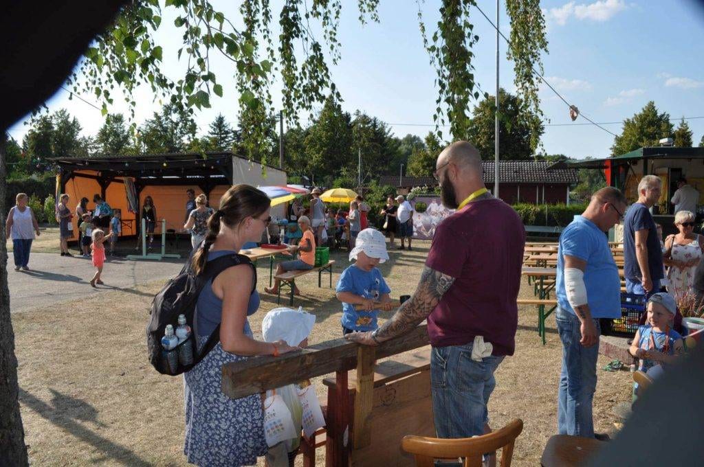 Familien bewegen sich zwischen Spielständen und Sitzbänken.