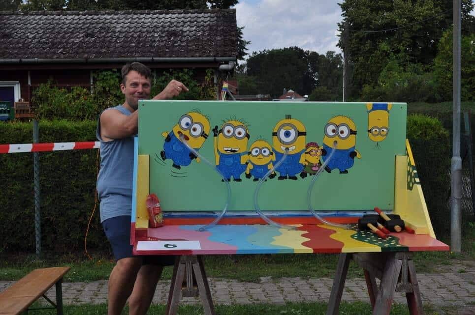 Kinderfest im Kleingartenverein Ein Helfer präsentiert einen bunt bemalten Minions-Spielstand.