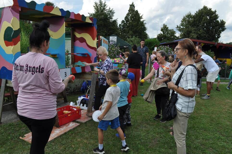 Kinderfest im Kleingartenverein Kinder und Erwachsene warten vor dem bunten Dosenwurfstand.