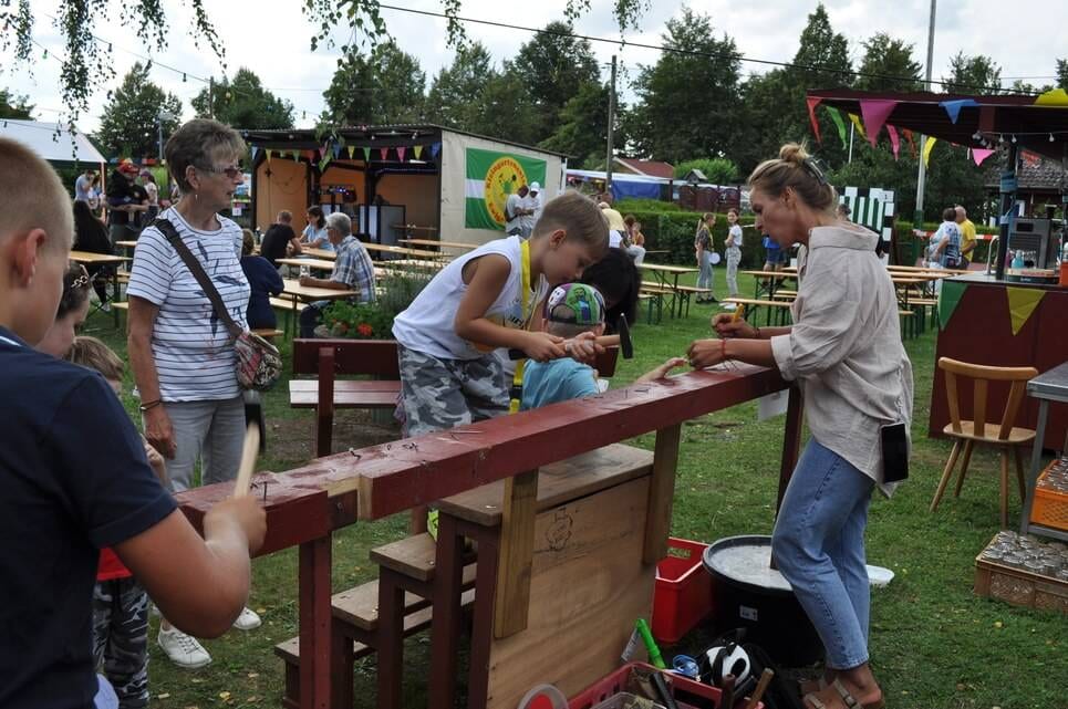 Kinderfest im Kleingartenverein Kinder bedienen ein Geschicklichkeitsspiel an einer roten Holzbahn.