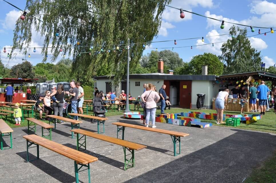 Kinderfest im Kleingartenverein Sitzbänke und Spielstationen verteilen sich über den sonnigen Festplatz.