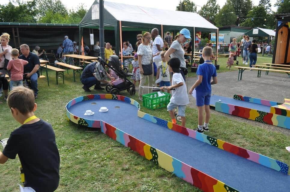 Kinderfest im Kleingartenverein Kinder spielen auf einer lang gestreckten bunt bemalten Balancierbahn.