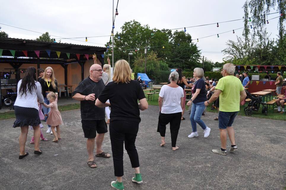 Unser Sommerfest 2023 Mehrere Gäste tanzen gemeinsam auf dem Festplatz.