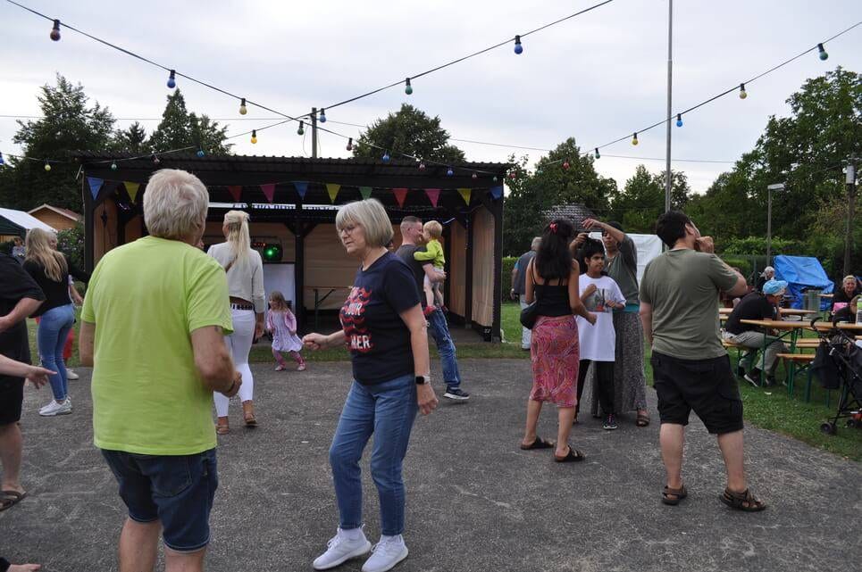 Unser Sommerfest 2023 Tanzpaare bewegen sich unter einer bunten Lichterkette.