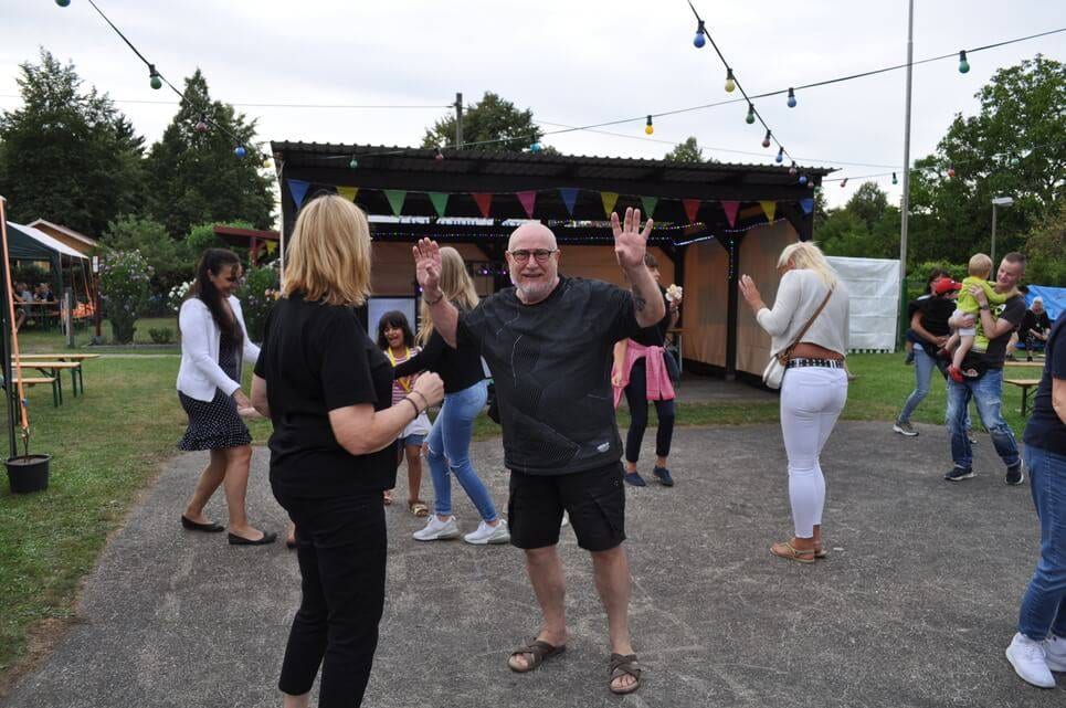 Unser Sommerfest 2023 Ein Mann posiert gut gelaunt zwischen tanzenden Gästen.