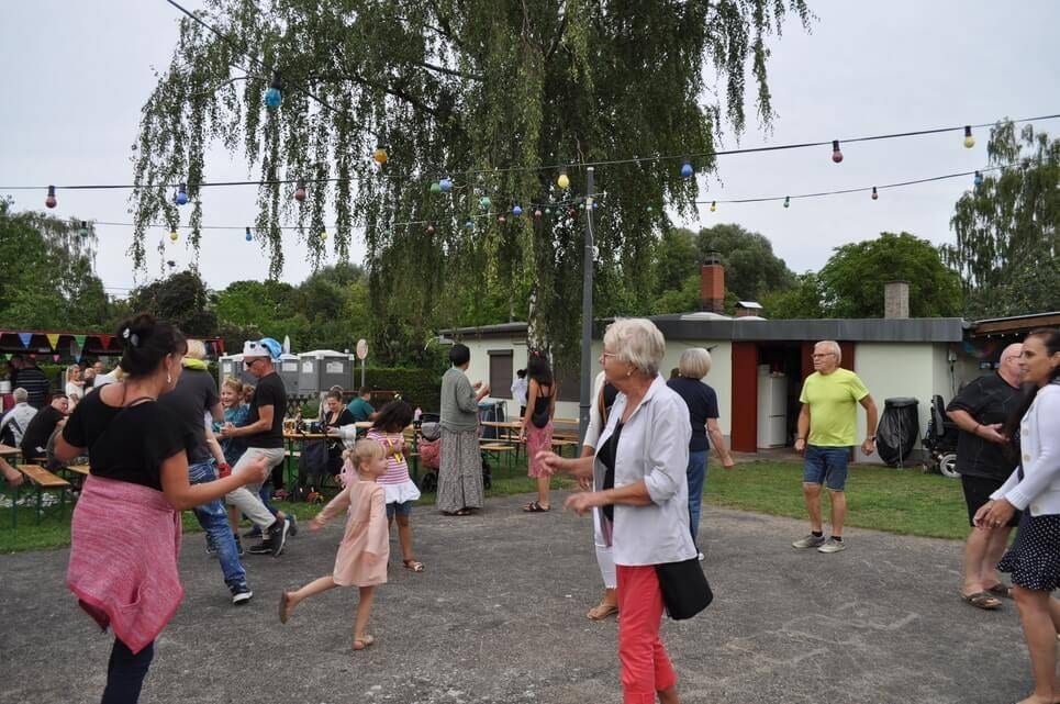 Unser Sommerfest 2023 Ein Kind und mehrere Erwachsene tanzen auf dem Festplatz.