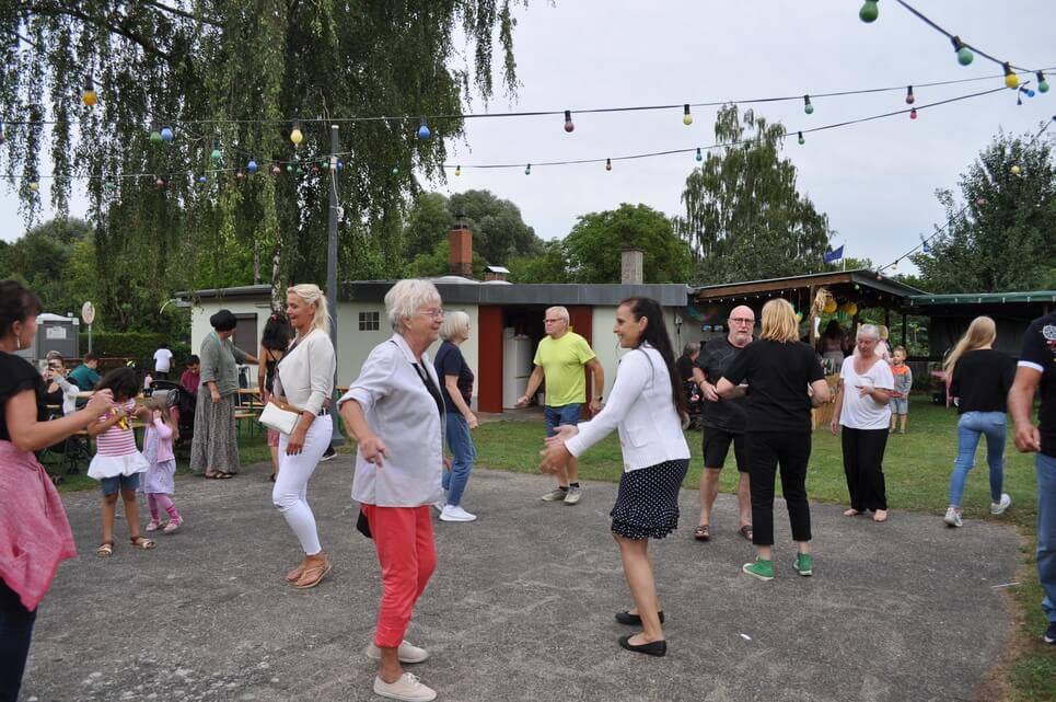 Unser Sommerfest 2023 Gäste verschiedener Generationen tanzen gemeinsam im Freien.
