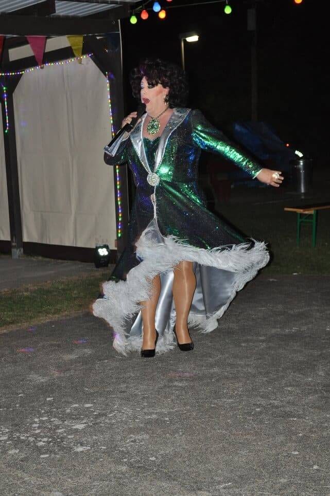 Unser Sommerfest 2023 Eine Bühnenkünstlerin tanzt in einem grün schimmernden Kleid.