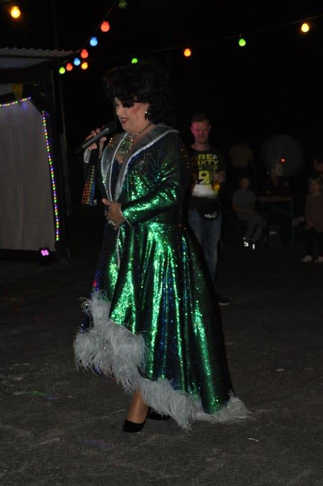 Unser Sommerfest 2023 Eine Künstlerin präsentiert einen langen grünen Bühnenmantel.