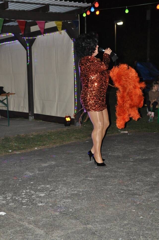 Unser Sommerfest 2023 Eine Künstlerin tanzt mit großem orangefarbenem Federschmuck.