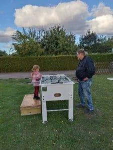 Ein Kind und ein Erwachsener spielen Tischfußball auf der Wiese beim Herbstfest.