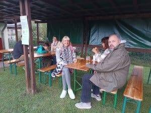 Mehrere Gäste sitzen an Biertischen unter dem Vordach beim Herbstfest.